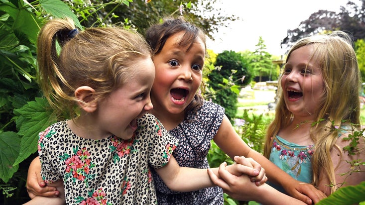 Three happy laughing girls in a garden